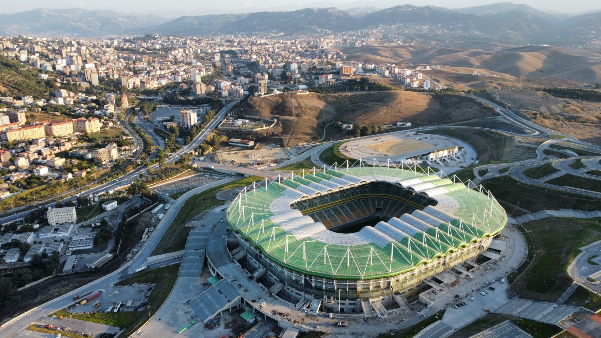 Aerial view of an Atlas Group-built stadium with athletics track and surrounding city